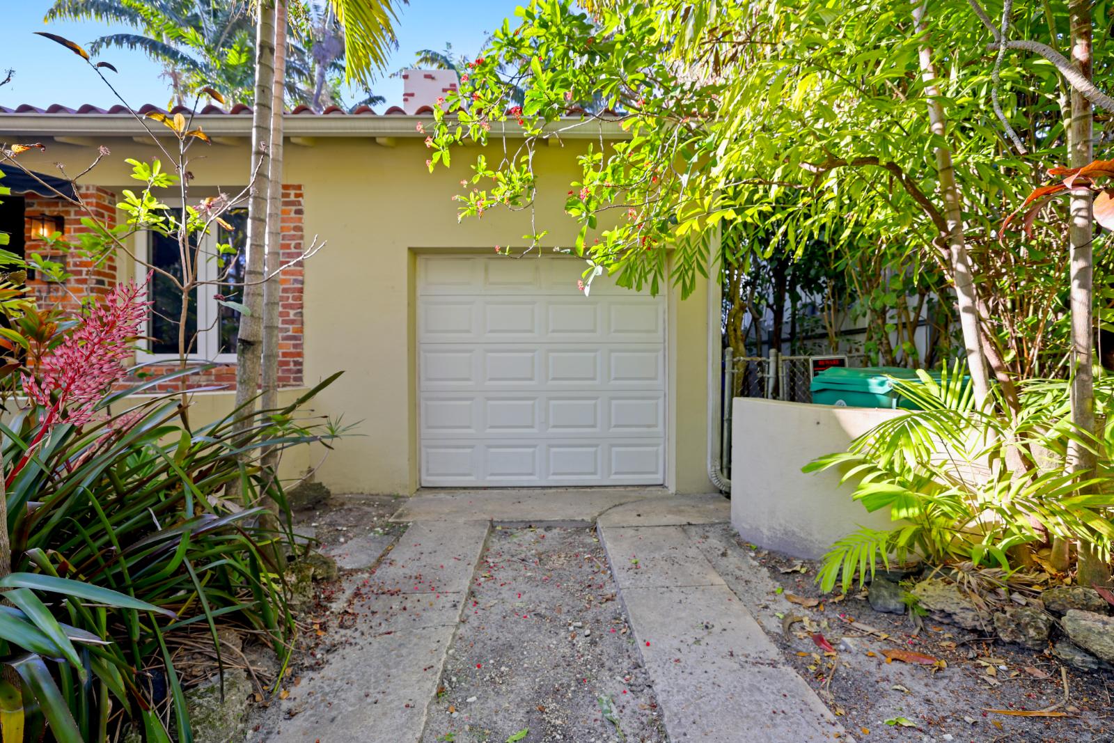 Front driveway and garage-side view framed by mature landscaping